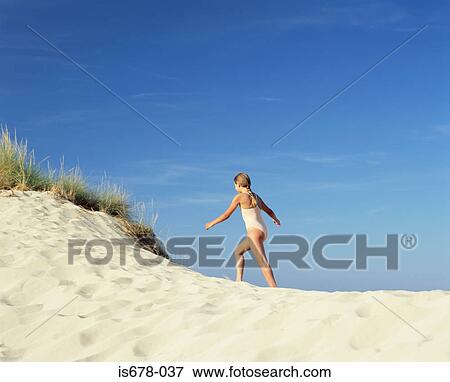 Stock Photo - Girl walking up a sand dune. Fotosearch