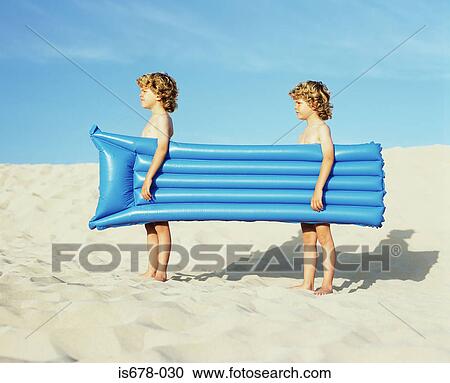 Twin boys carrying an inflatable View Large Photo Image Stock Image - Twin boys carrying an inflatable. Fotosearch