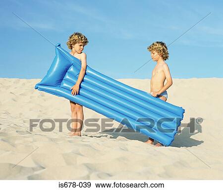 Twin boys carrying an inflatable View Large Photo Image Stock Photo - Twin boys carrying an inflatable. Fotosearch