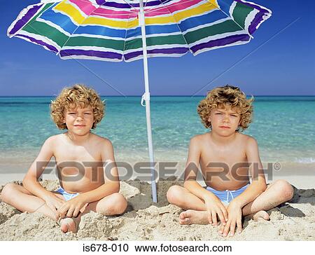 Twin boys under a sun umbrella View Large Photo Image Stock Image - Twin boys under a sun umbrella. Fotosearch