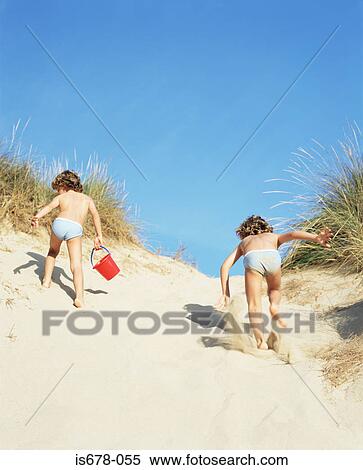 Twins running up a sand dune View Large Photo Image Stock Photography - Twins running up a sand dune. Fotosearch