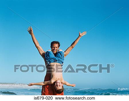 Stock Image - Father holding son upside down. Fotosearch