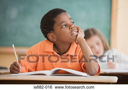 Stock Photograph - Schoolboy daydreaming in classroom. Fotosearch