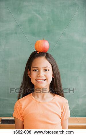 Stock Photo - Schoolgirl balancing an apple on her head. Fotosearch