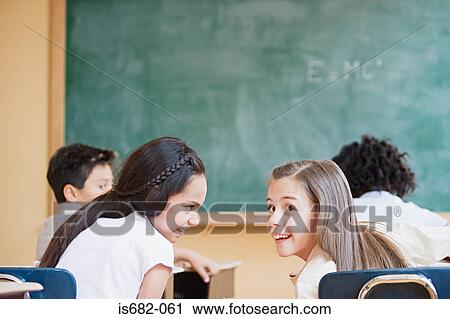 Stock Image - Schoolgirls talking in classroom. Fotosearch