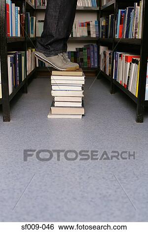 Person standing on books in library View Large Photo Image Stock Photograph - Person standing on books in library. Fotosearch