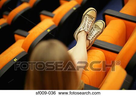 Stock Photograph - Woman stretching out her legs in lecture theatre. Fotosearch