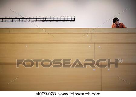 Stock Photo - Young man alone in a lecture theatre. Fotosearch