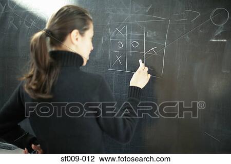 Young woman drawing noughts and crosses on a blackboard View Large Photo Image Stock Image - Young woman drawing noughts and crosses on a blackboard. Fotosearch