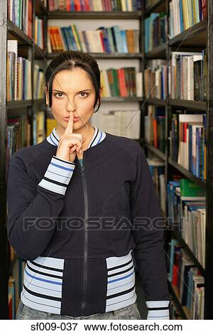 Stock Photo - Young woman putting her fingers to her lips . Fotosearch