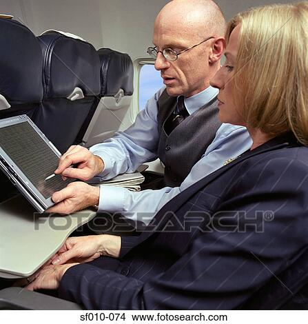Business people using laptop on an aeroplane View Large Photo Image Picture - Business people using laptop on an aeroplane. Fotosearch