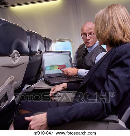 Business people using laptop on an aeroplane View Large Photo Image Stock Photo - Business people using laptop on an aeroplane. Fotosearch