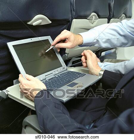 Business people using laptop on an aeroplane View Large Photo Image Stock Photograph - Business people using laptop on an aeroplane. Fotosearch