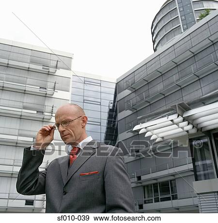 Businessman adjusting his glasses View Large Photo Image Stock Photo - Businessman adjusting his glasses. Fotosearch