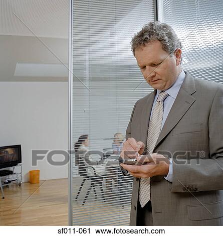 Businessman using a handheld computer View Large Photo Image Stock Image - Businessman using a handheld computer. Fotosearch