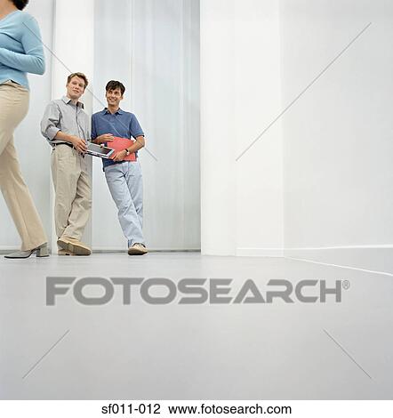 Stock Image - Male office workers watching woman walk by. Fotosearch