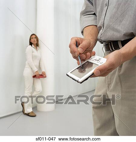 Stock Photo - Man using a handheld computer. Fotosearch
