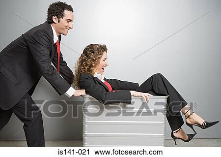 Stock Image - Businessman pushing businesswoman in wheelie bin. Fotosearch