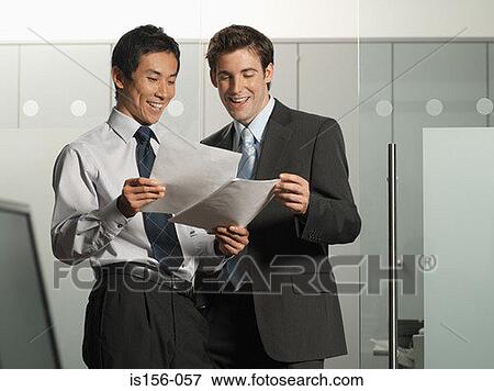 Stock Photo - Colleagues smiling at paperwork. Fotosearch