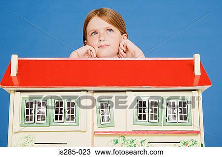 Stock Image - Girl leaning on doll house. Fotosearch