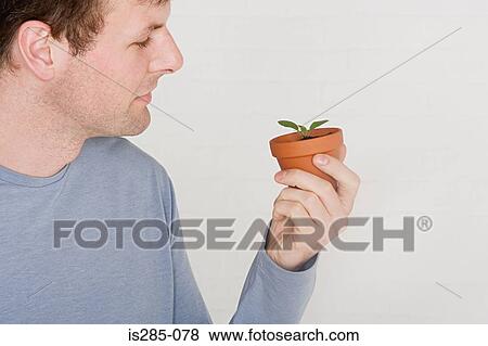 Man holding a small plant View Large Photo Image Stock Photo - Man holding a small plant. Fotosearch