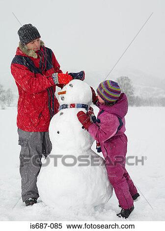Stock Photography - Father and daughter making a snowman. Fotosearch