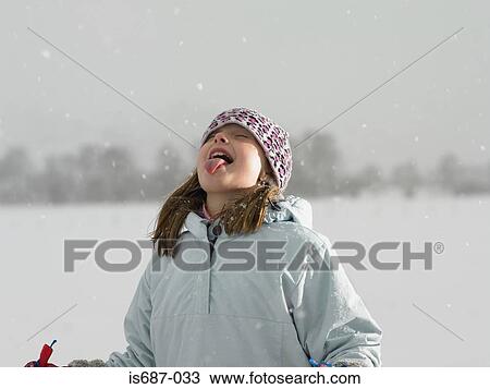 Stock Image - Girl catching snow on her tongue. Fotosearch
