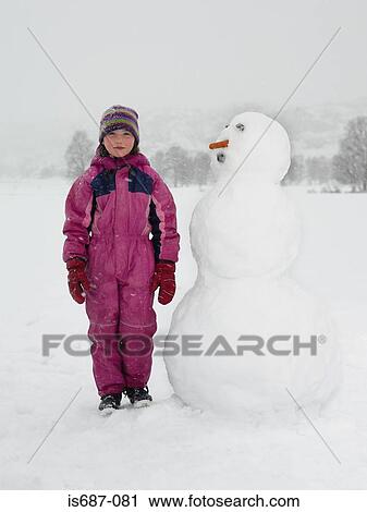 Girl standing next to snowman View Large Photo Image Stock Image - Girl standing next to snowman. Fotosearch