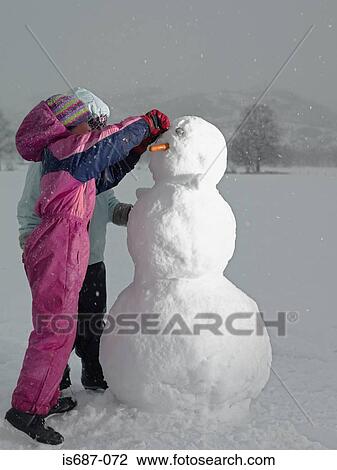 Girls making a snowman View Large Photo Image Stock Image - Girls making a snowman. Fotosearch