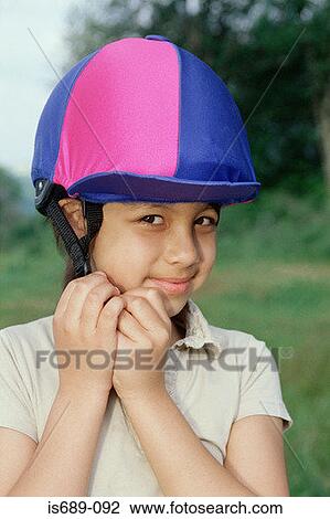 Stock Image - Girl adjusting riding hat. Fotosearch