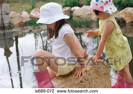 Stock Image - Girls by a pond. Fotosearch