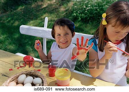 Stock Image - Girls painting eggs and hands. Fotosearch