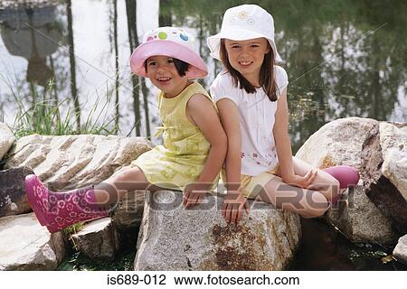 Stock Image - Girls sitting on rocks. Fotosearch