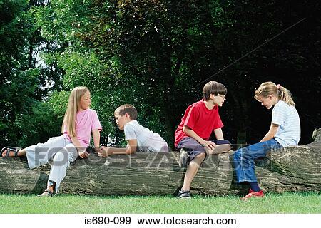 Stock Photo - Boys and girls sitting on a log. Fotosearch