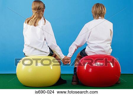 Girl and boy sitting on exercise balls holding hands View Large Photo Image Picture - Girl and boy sitting on exercise balls holding hands. Fotosearch