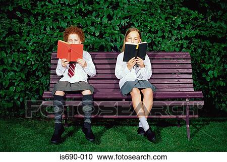 Stock Image - Schoolgirls reading on a bench. Fotosearch