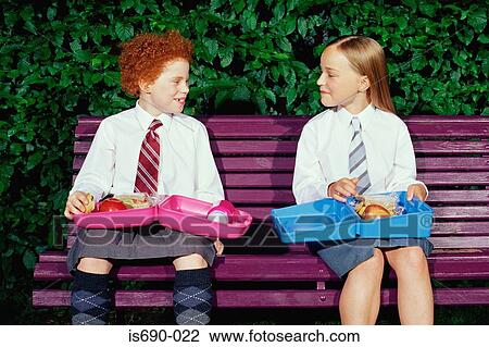 Stock Image - Schoolgirls with packed lunches. Fotosearch