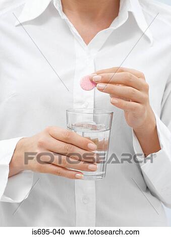 Stock Image - Man holding a hangover pill. Fotosearch