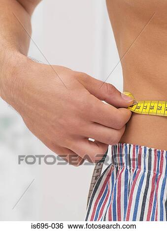 Man measuring his stomach View Large Photo Image Stock Photograph - Man measuring his stomach. Fotosearch