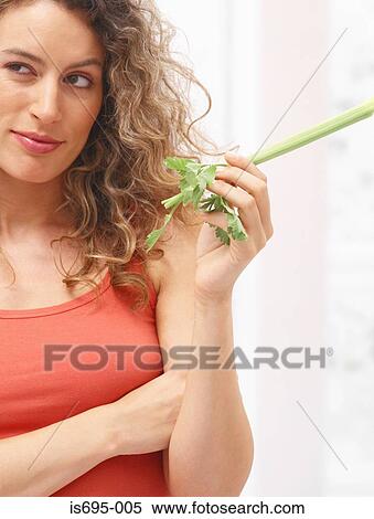 Woman holding a stick of celery View Large Photo Image Stock Photography - Woman holding a stick of celery. Fotosearch