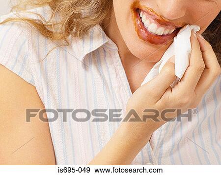 Stock Photo - Woman wiping chocolate from mouth. Fotosearch