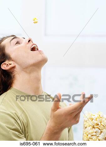 Young man eating popcorn View Large Photo Image Stock Image - Young man eating popcorn. Fotosearch
