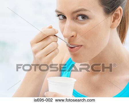 Stock Image - Young woman eating yoghurt. Fotosearch