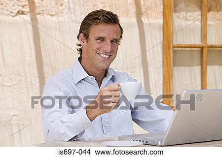 Picture - Man with teacup and laptop computer. Fotosearch