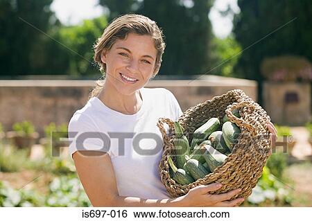 Woman holding a basket of courgettes View Large Photo Image Stock Photograph - Woman holding a basket of courgettes. Fotosearch