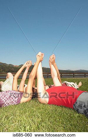 Friends lying down and holding hands View Large Photo Image Stock Image - Friends lying down and holding hands. Fotosearch
