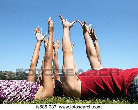Friends lying down and raising arms View Large Photo Image Stock Photo - Friends lying down and raising arms. Fotosearch