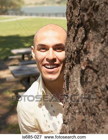 Man by tree trunk View Large Photo Image Stock Photo - Man by tree trunk. Fotosearch