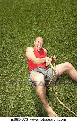 Stock Image - Man on the grass with rope. Fotosearch