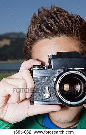 Stock Image - Young man holding a camera. Fotosearch